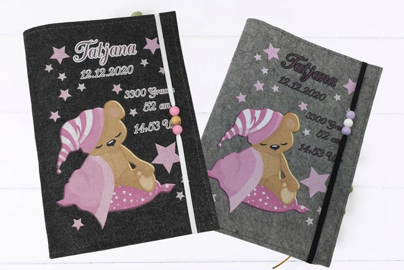 Weiche U-Heft-Hülle aus Filz mit schlafendem Teddybär und rosa Details – mit Platz für Geburtsdaten.