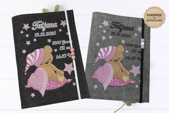 Illustrative Filzhülle für das Untersuchungsheft mit rosa Teddybärmotiv und dekorativen Sternen.