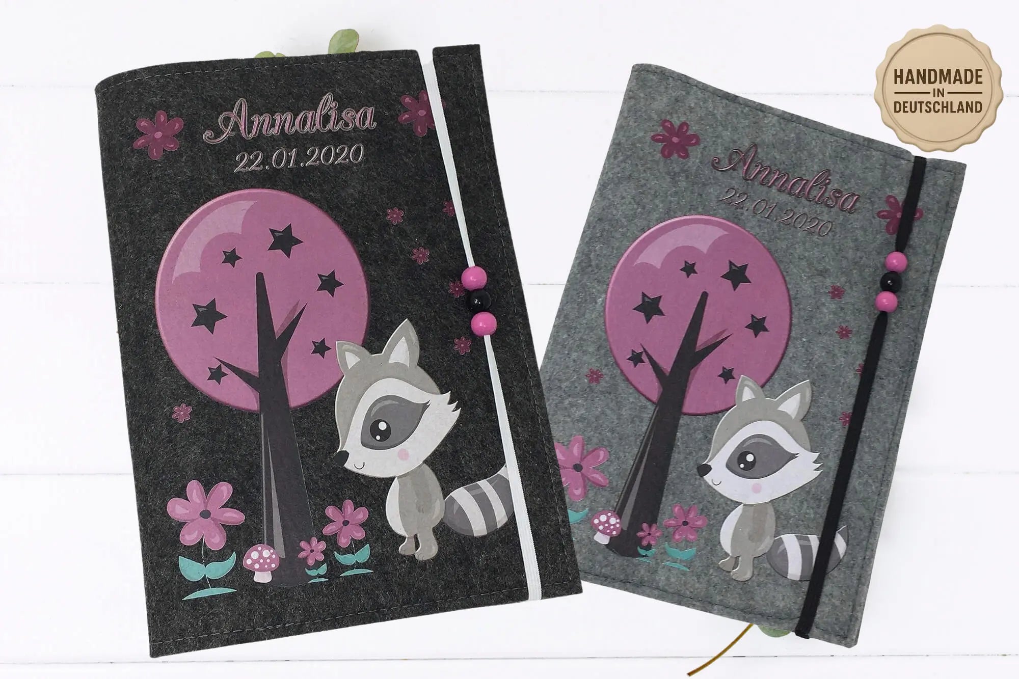 Detailreiche U-Heft-Hülle mit lila Baum, Blüten und Waschbär – handgemacht und liebevoll gestaltet.