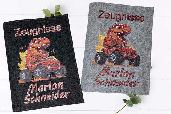 Zwei Zeugnismappen mit Dinosaurier-Motiv – Feuer speiender T-Rex fährt roten Monstertruck – auf Filz in Dunkelgrau und Hellgrau.