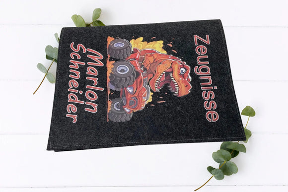 Dino-Zeugnismappe in Hell- und Dunkelgrau, jeweils mit rotem Monstertruck und Vulkanausbruch im Hintergrund.