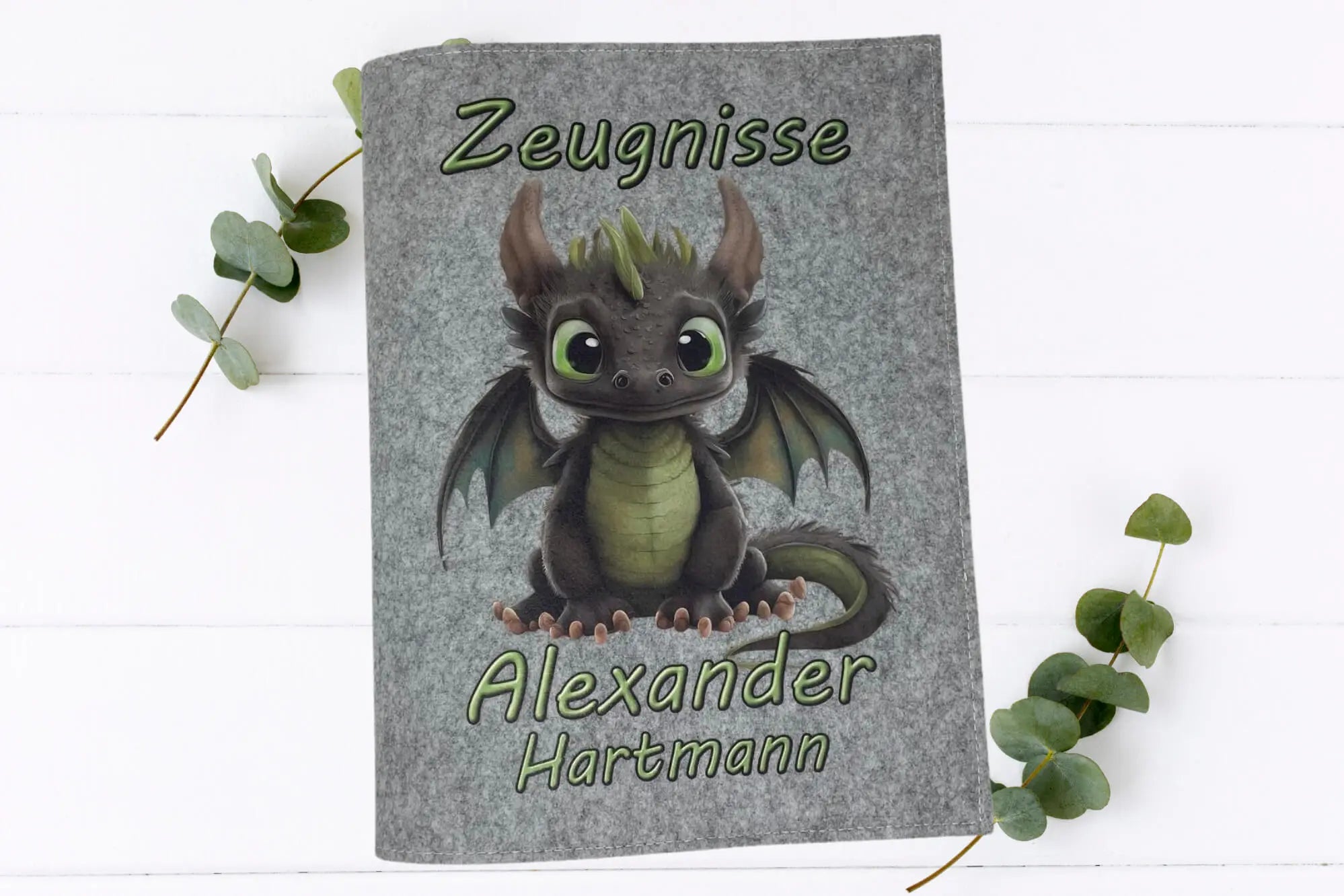 Filzhüllen für Schulzeugnisse mit putzigem Drachenmotiv, grün leuchtendem Bauch und großen Kulleraugen.