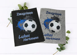 Personalisierte Zeugnismappen aus Filz mit Fußballmotiv und blauen Farbspritzern – mit Namensaufdruck in Hell- und Dunkelgrau.