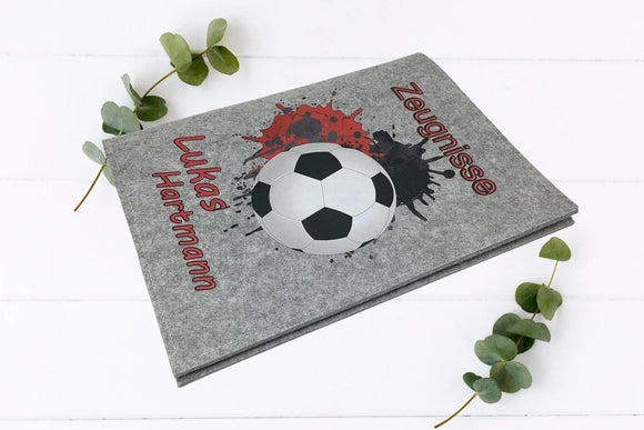 Moderne Zeugnismappen mit Fußball, rotem Graffiti-Effekt und Namensaufdruck – in zwei Farbausführungen.