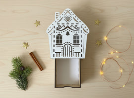 Geschenkschachtel Hausform aus Holz mit filigranen Lasercut-Details auf hellem Hintergrund