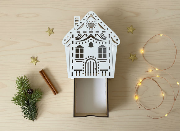 Geschenkschachtel Hausform aus Holz mit filigranen Lasercut-Details auf hellem Hintergrund