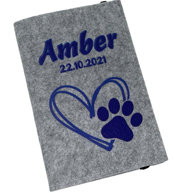 Hellgraue Filzhülle für Heimtierausweis mit dunkelblauem Herz- und Pfotenmotiv.