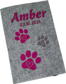 Graue Filzhülle für Heimtierausweis mit personalisiertem Namensaufdruck und Pfoten in Pink.