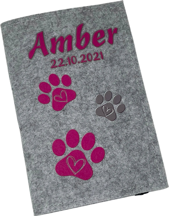 Graue Filzhülle für Heimtierausweis mit personalisiertem Namensaufdruck und Pfoten in Pink.