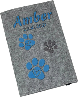 Graue Filzhülle für Heimtierausweis mit Name, Datum und hellblauen Pfotenabdrücken.