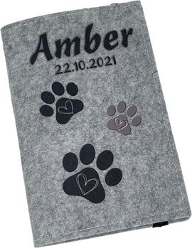 Graue Filzhülle für Heimtierausweis mit Namensaufdruck und Pfötchen in Schwarz.