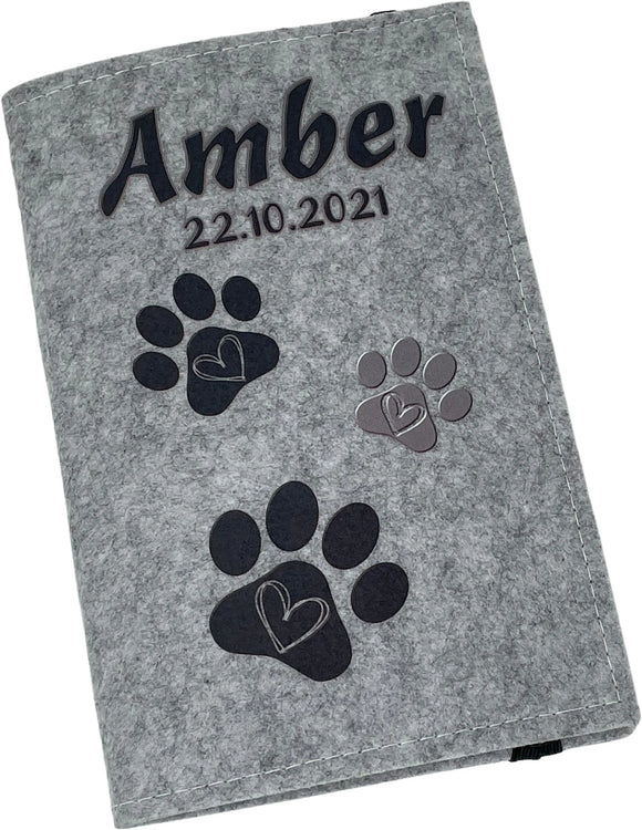 Graue Filzhülle für Heimtierausweis mit Namensaufdruck und Pfötchen in Schwarz.