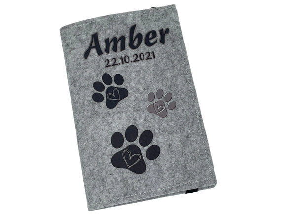 Pflegeleichte Tierausweishülle mit schwarzen Pfotenabdrücken und Herzsymbol.