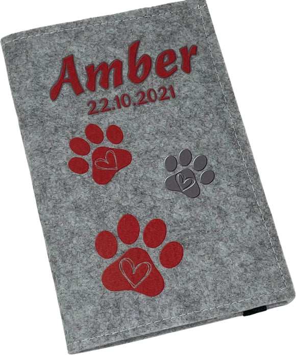 Personalisierte Filzhülle für Heimtierausweis mit roten Pfotenabdrücken.